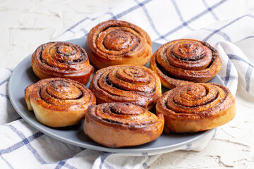 baked cinnamon buns on grey plate on light background with checkered napkin