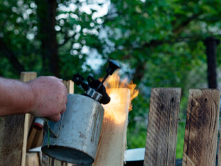 Hand of a man burning a board with a blowtorch