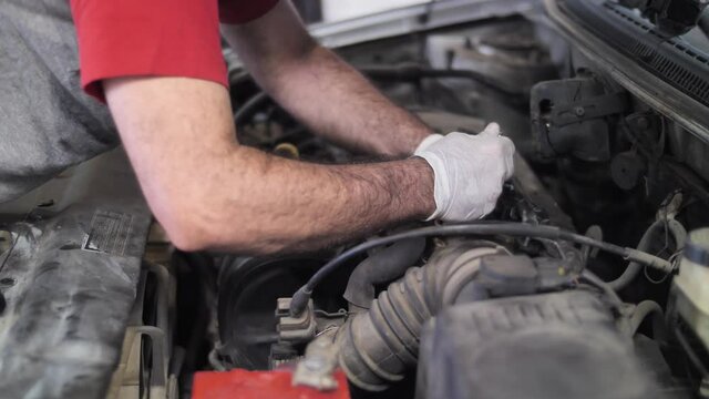 Mechanic at work, repairing car engine on open hood, oil changing procedure