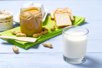american breakfast milk and peanut butter. Peanut butter, white bread with glass of milk on blue wooden background.