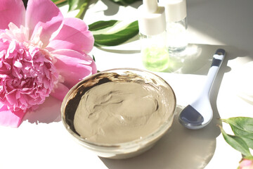 Cosmetic face masks with natural oil in a composition with flowers on a white background.