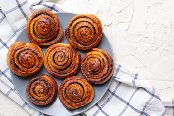 baked cinnamon buns on grey plate on light background with checkered napkin