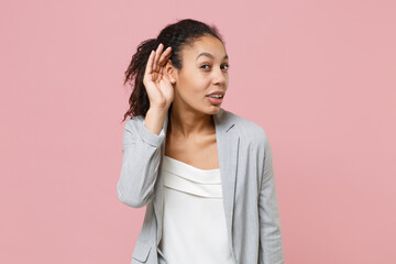 Curious african american business woman in grey suit white shirt posing isolated on pink background...