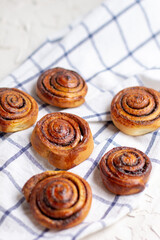 baked cinnamon buns on light background with checkered napkin