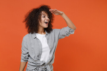 Excited young african american woman girl in gray casual clothes isolated on orange background...