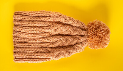 Handmade knitted winter hat on yellow background