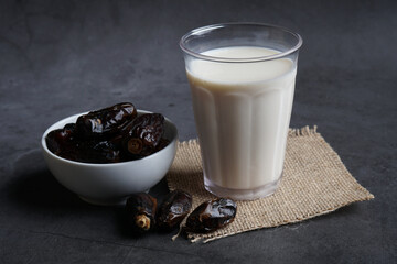 Dates milk and dates in the bowl on grey background.
