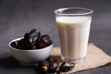 Dates milk and dates in the bowl on grey background.
