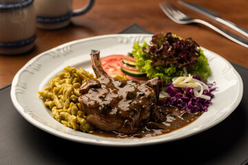 rib eye steak with spaetzle salad on leather mat and wooden table