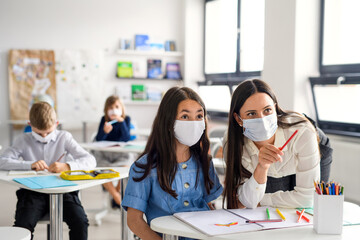 Teacher and children with face mask back at school after covid-19 quarantine and lockdown.