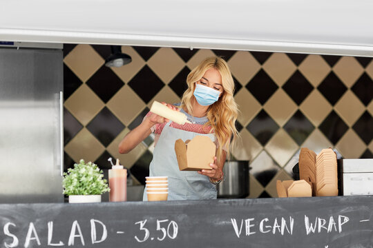 Street Sale And People Concept - Young Saleswoman Wearing Face Protective Medical Mask For Protection From Virus Disease Making Wok At Food Truck