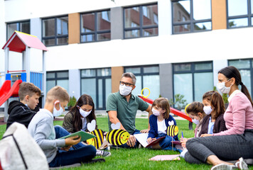 Group of cheerful children learning outdoors at school after covid-19 quarantine and lockdown.