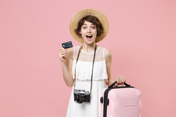 Excited young tourist girl in summer dress hat with photo camera isolated on pink background....