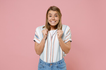 Excited young blonde woman girl in casual striped shirt posing isolated on pastel pink background....