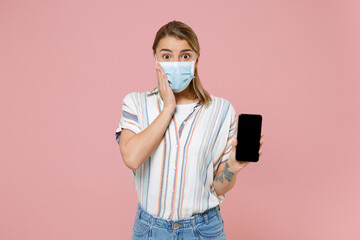 Amazed girl in striped shirt face mask isolated on pink background. Epidemic pandemic coronavirus...