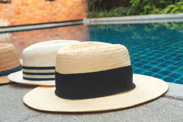 Straw hats at the pool edge with palm reflections in the water. Relax vacation, sun protection, travel fashion concept