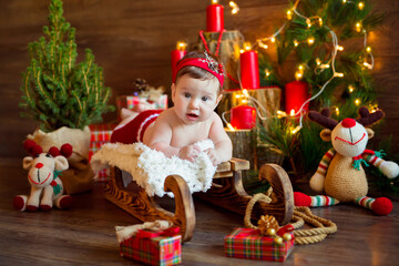 Happy Santa girl lies on a wooden sled with gifts surrounded by Christmas trees with garlands and toys. New Years is soon.