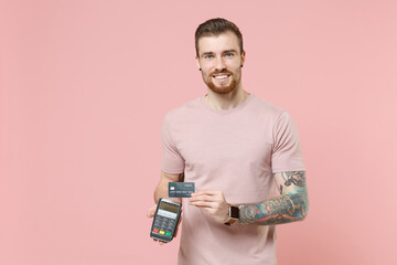 Smiling young bearded tattooed man guy in pastel t-shirt isolated on pink background. People...