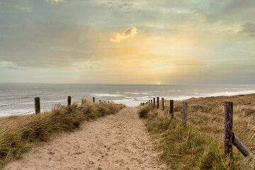 Sonnenuntergang über der Nordsee mit Blick von einem sandigen Dünenpfad auf das Meer bei Noordwijk, Niederlande
