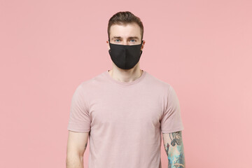Young tattooed man guy in pastel casual t-shirt, black face mask posing isolated on pink wall background studio portrait. People sincere emotions lifestyle concept. Mock up copy space. Looking camera.