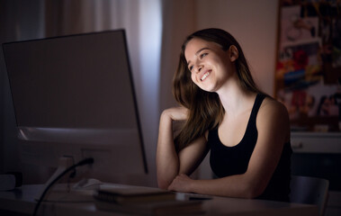 Happy young girl with computer at night smiling, online dating concept.