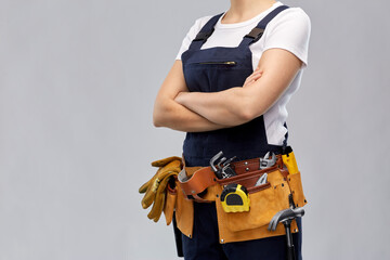 repair, construction and building concept - woman or builder with working tools on belt over grey...