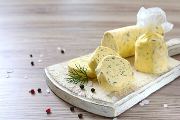 Butter with a herb for sandwiches and steak. Portion of Herb Butter sliced on a wooden board. Homemade italian food. Selective focus.