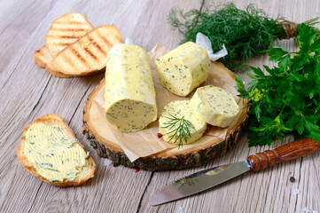 Butter with a herb for sandwiches and steak. Portion of Herb Butter sliced on a wooden board. Homemade italian food.