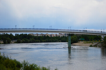 Fototapeta premium bridge over the river in the city. on the right is a small beach, in the background are multi-storey buildings