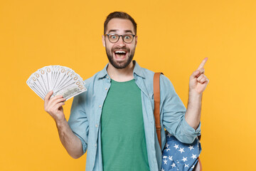 Excited young man student in glasses backpack isolated on yellow background. Education in high...