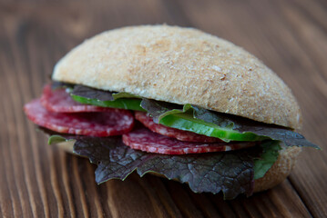 Fresh whole grain sandwich with salami and purple basil leaves