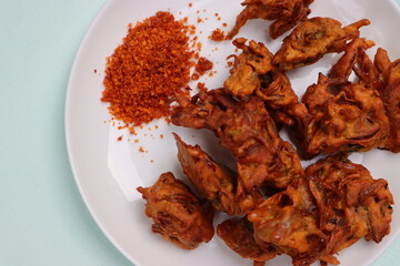 Crispy kanda pakora, kanda bhaji or onion fritters. A road side snack served with red garlic chutney. favourite monsoon snack in India.  