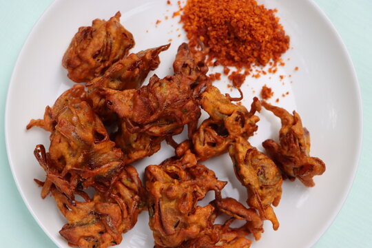 Crispy kanda pakora, kanda bhaji or onion fritters. A road side snack served with red garlic chutney. favourite monsoon snack in India.  