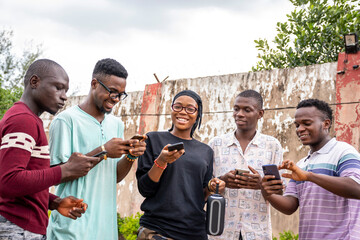 a group of young africans using their phones, hanging out together, students leisure on campus
