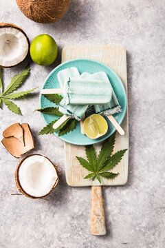 ice cream popsicle bars with coconut slices, cannabis on concrete background.