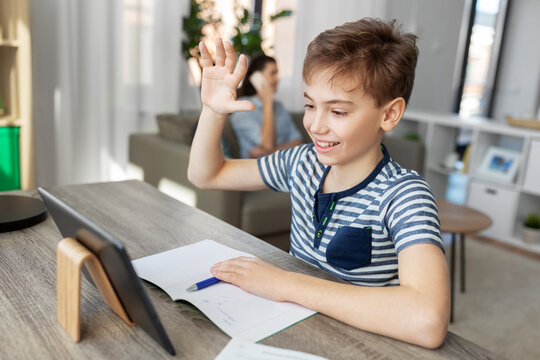 e-learning, education and school concept - happy student boy with tablet pc computer having video call at home
