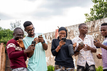 a group of young africans using their phones, hanging out together, students leisure on campus, having discussions