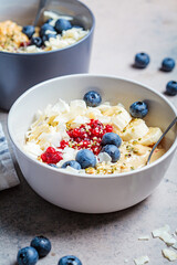 Oatmeal bowl with banana, berries, hemp seeds and coconut slices. Healthy vegan breakfast concept.