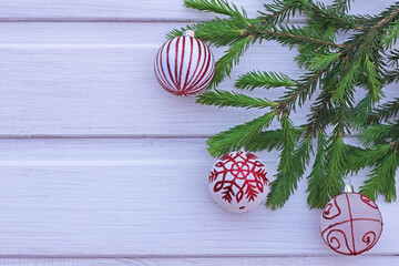 Young green spruce branches and toys on a white wooden background. New Year's composition. Copy space greeting card