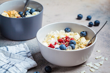 Oatmeal bowl with banana, berries, hemp seeds and coconut slices. Healthy vegan breakfast concept.