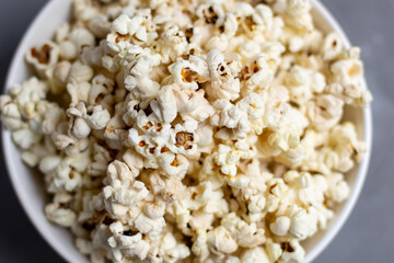 Popcorn in white bowl on grey table. Top view with copyspace