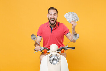 Surprised young bearded man guy in summer clothes driving moped isolated on yellow background....