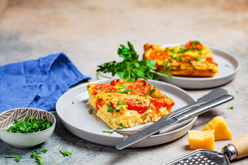 Traditional egg frittata (omelet) with tomatoes and cheese in gray plate.