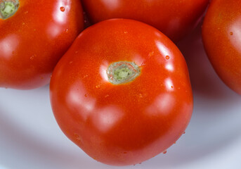 Nahaufnahme einer rote Tomate mit Wassertropfen auf einem Teller
