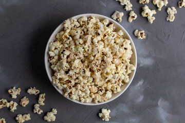 Obraz na płótnie Canvas Popcorn in white bowl on grey table. Top view with copyspace