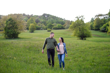 Happy couple walking outdoors in spring nature, holding hands.