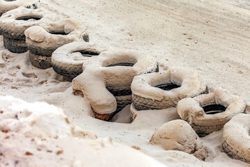 Fototapeta na wymiar Old tires of cars installed along the highway rally in winter powdered snow
