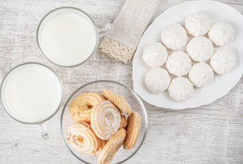 White round marshmallows, two cups of milk, cookies in powdered sugar. High key horizontal frame