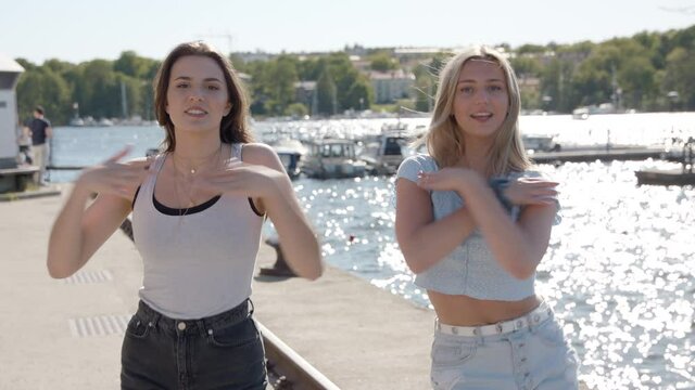 Two young women recording a TikTok video in the harbour.