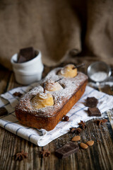 Chocolate cake with pears and chocolate with icing sugar on a wooden table